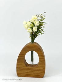 A wooden dome shaped vase with a glass test tube containing a jonquil and wattle sprig made from Elm timber on white background