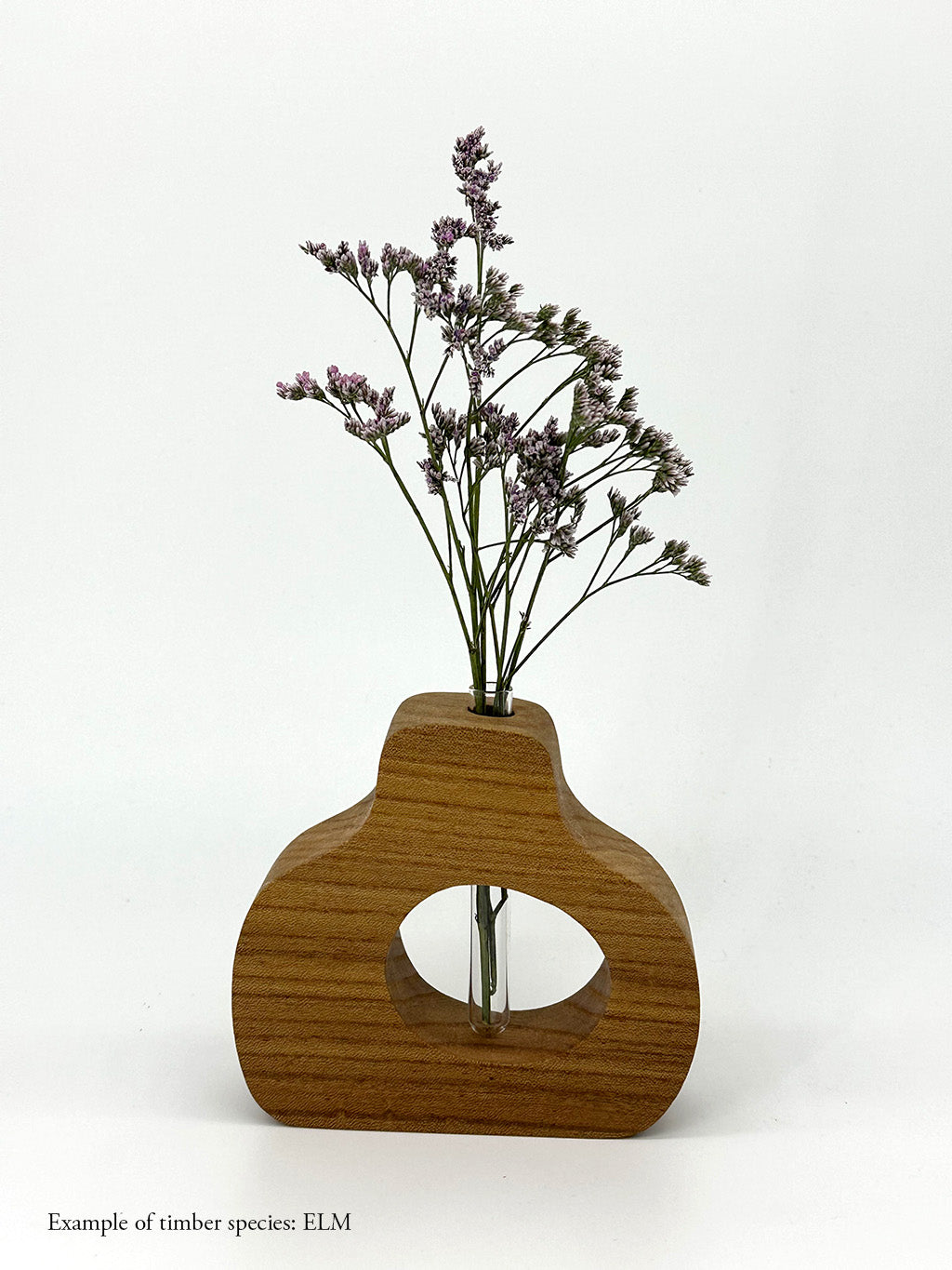 A wooden pear shaped vase with a glass test tube containing a plant sprig made from Elm timber on a white background