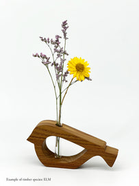 A wooden bird shaped vase with a glass test tube containing a yellow daisy and plant sprig made from Elm timber on white background