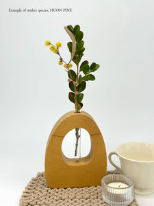 A wooden dome shaped vase with a glass test tube containing a japanese box and wattle sprig made from Huon Pine timber on white background