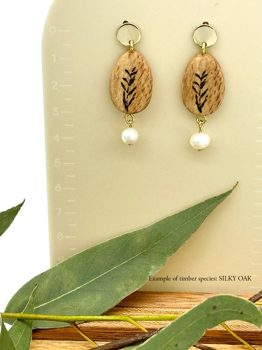 handmade wood and freshwater pearl earrings with eucalyptus in foreground